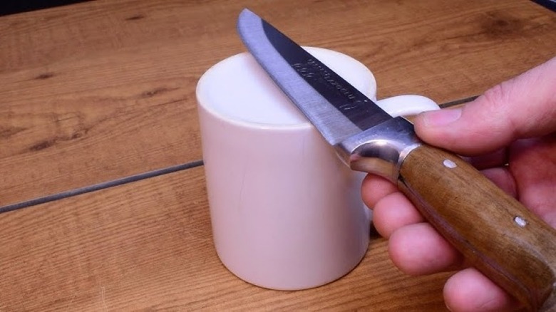 person sharpening knife coffee mug