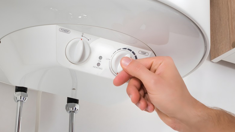 Hand adjusting temperature on white water heater