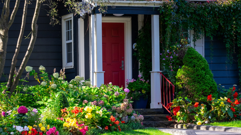 A blue house with a red front door and a lush garden