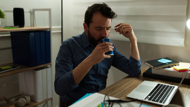 Man drinking beverage in blue can in home office