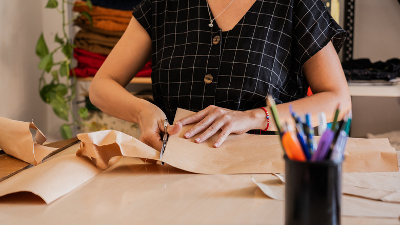 Woman cuts parchment paper at crafting table.