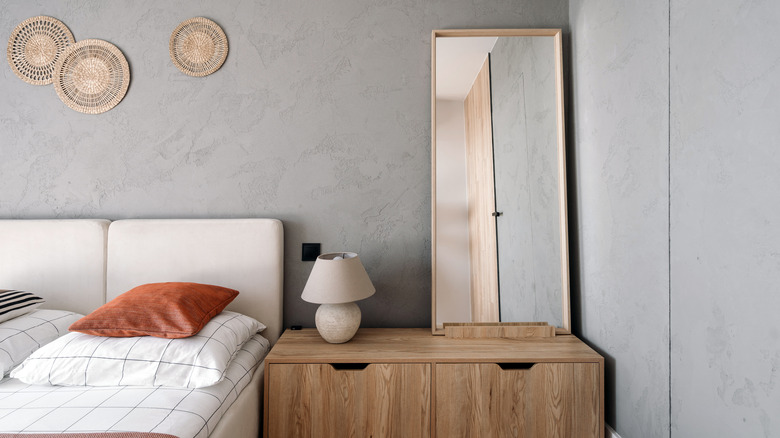 Minimalist mirror against bedroom wall.