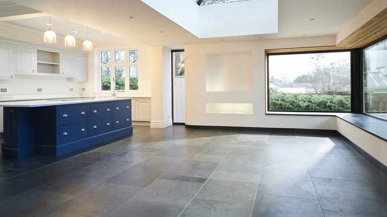 new unfurnished kitchen with granite tiles, white walls and cabinets and a blue kitchen island