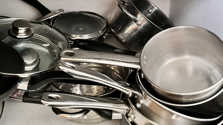 disorganized pots and pans in cabinet