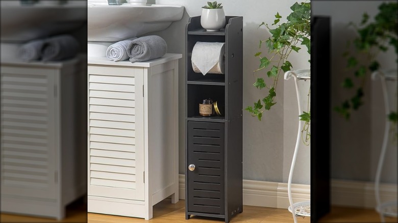 Black toilet paper stand in a bathroom with toilet paper rolls