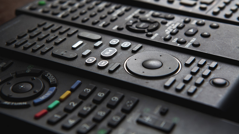 Close-up shot of black TV remotes lined up on table