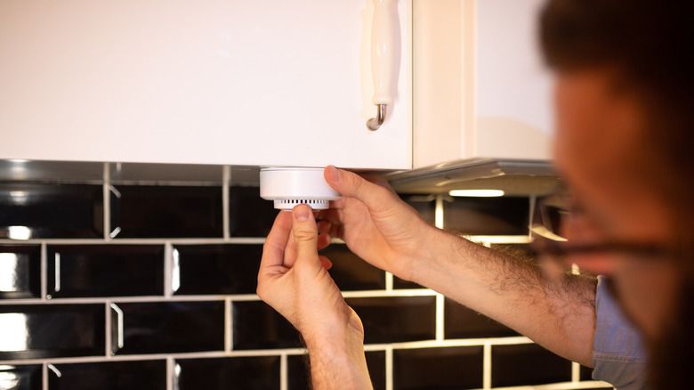 Man installing a Wi-Fi smoke sensor in the kitchen