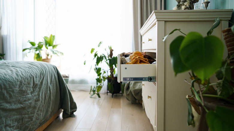 A dresser drawer is left open in an otherwise tidy bedroom.