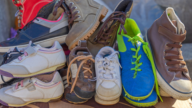 A pile of boots and shoes create a cluttered mess.