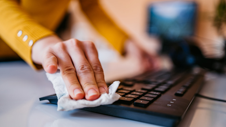 Woman wiping laptop keyboard