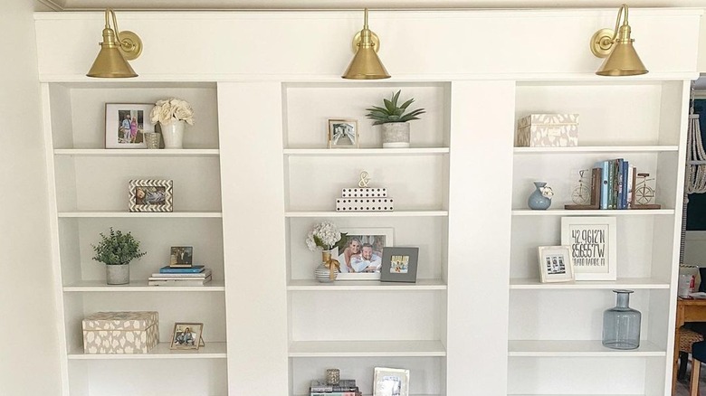 White bookcases with gold sconces