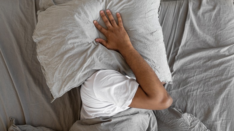 Person covering head with pillow