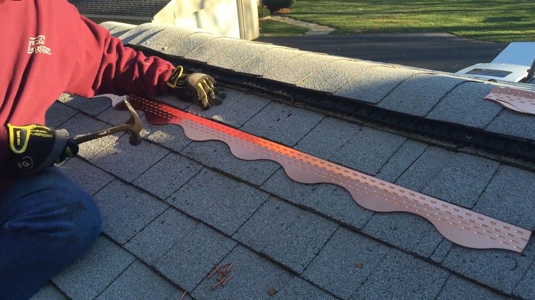 A roofing professional installing copper roofing strips