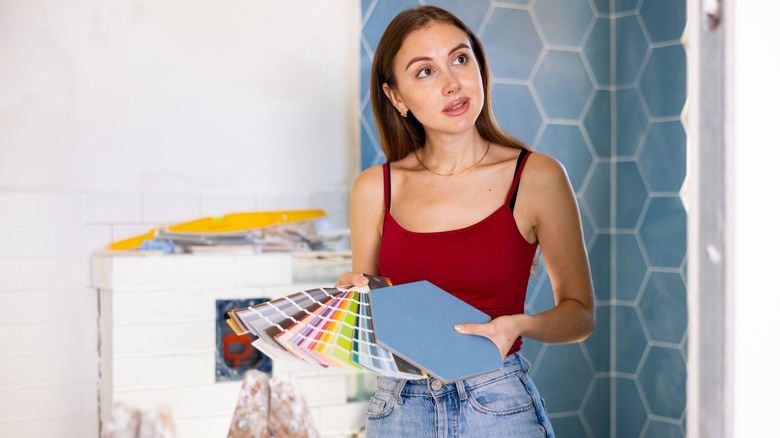 Woman in red shirt holding color palettes in bathroom