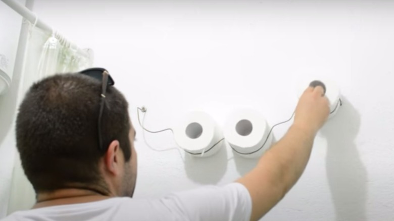 man hanging wire cloud toilet paper holder