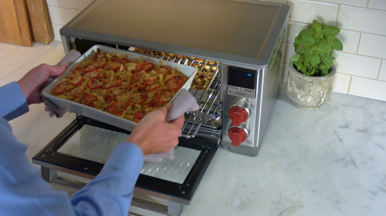 person taking dish out of wolf countertop oven