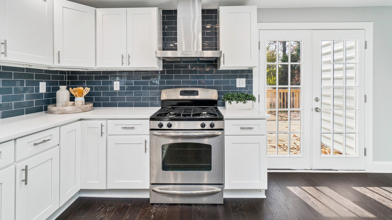 A white kitchen with blue glass subway tile backsplash