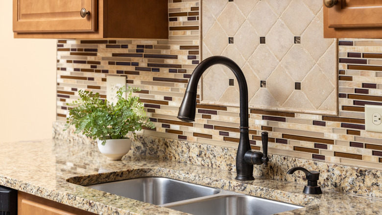 A brown glass mosaic tile backsplash behind a kitchen sink