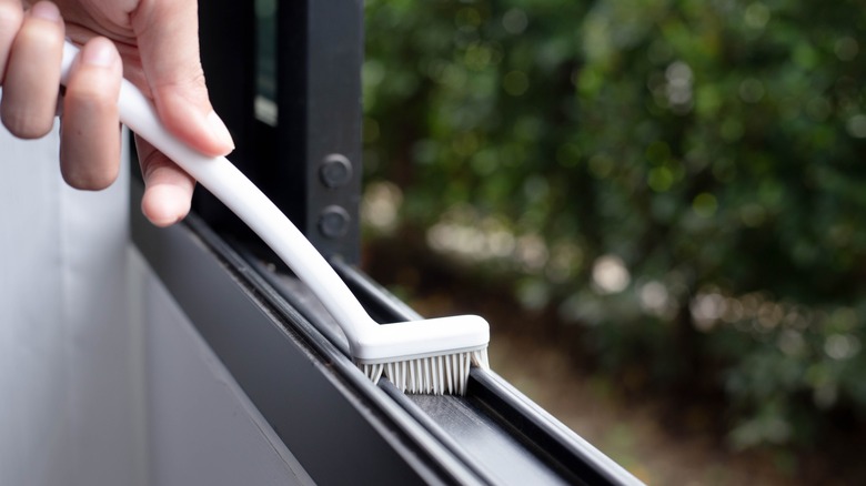 Person cleaning sill of open window