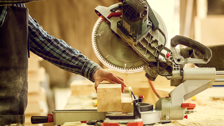 Person cutting wood with miter saw