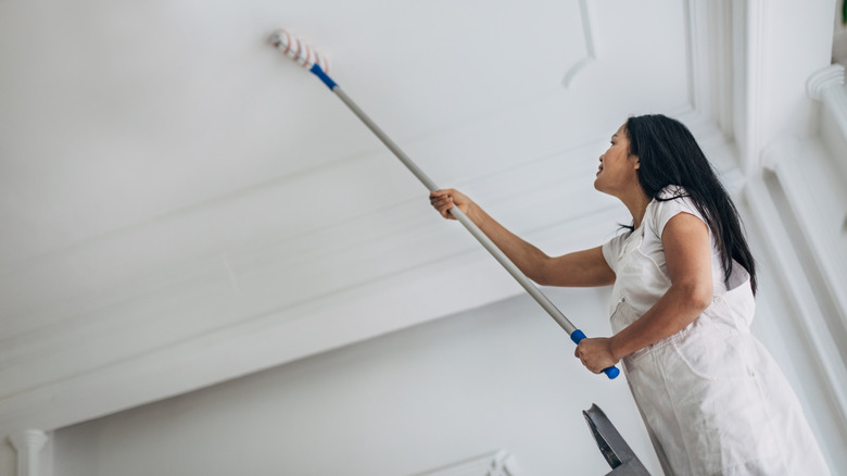 woman painting ceiling white with roller