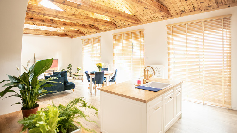 Beautiful, cozy living room with light kitchen island, bamboo blinds and high wooden ceiling.