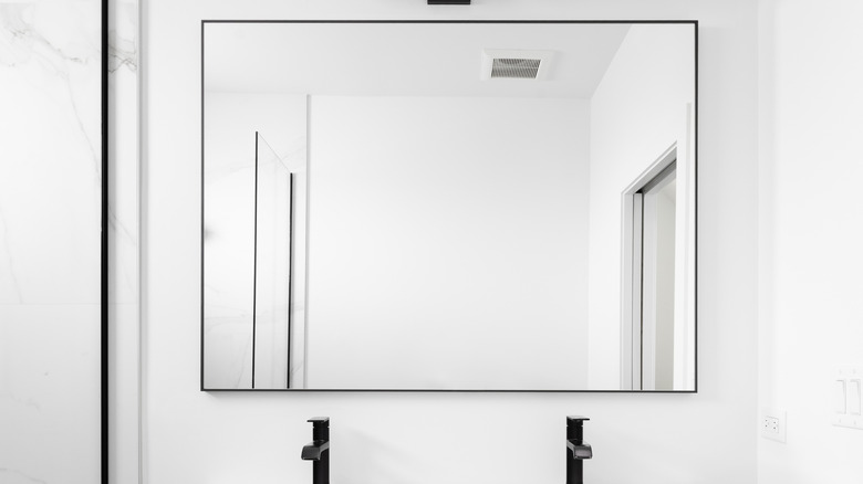 A black-bordered mirror with black faucet handles