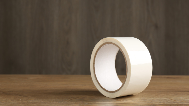 A roll of masking tape sitting on a wooden table top