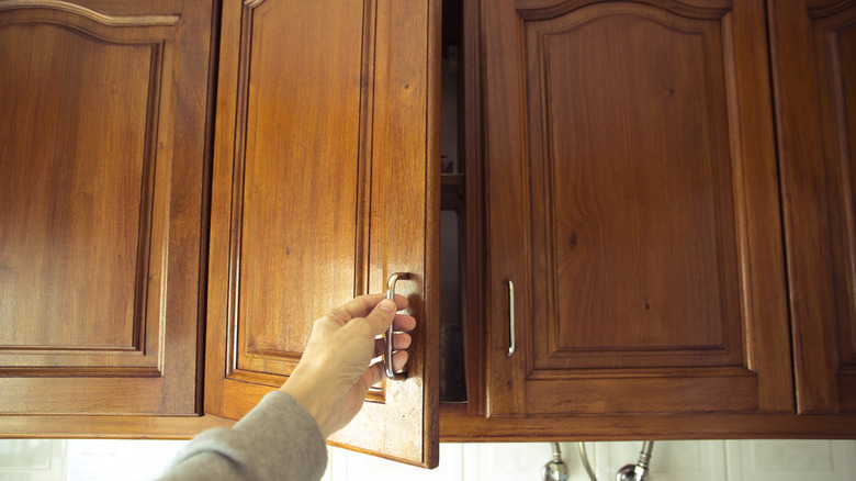 person opening wooden cabinet door