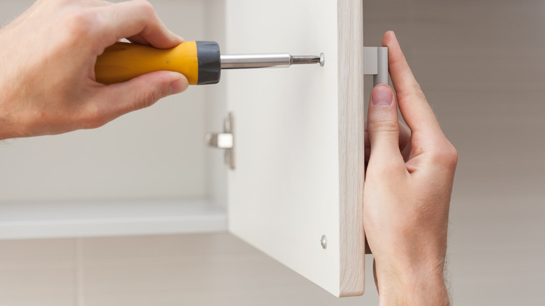 person adding new cabinet hardware