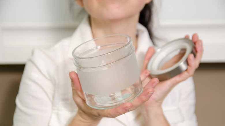 Woman holding an open empty glass jar.