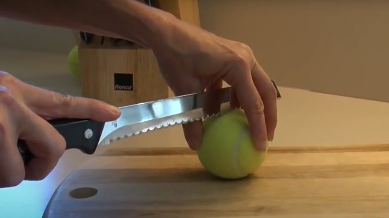 Woman cutting tennis ball in half