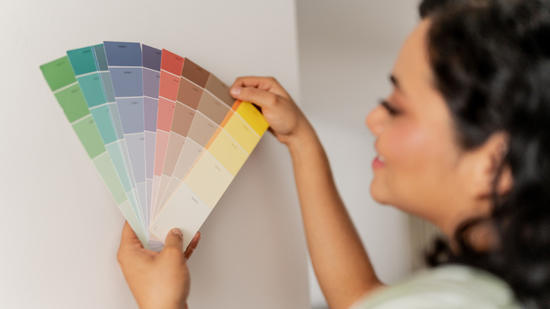 Woman looking at color swatches against white wall