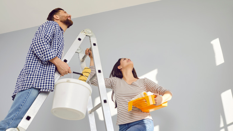 Couple holding painting supplies