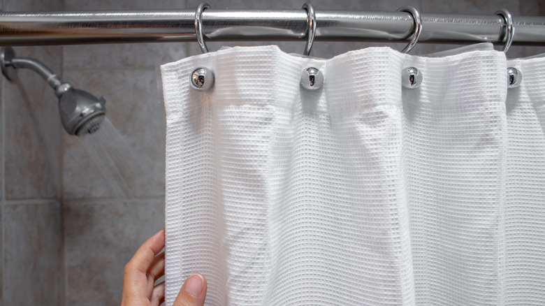 Person touching shower curtain