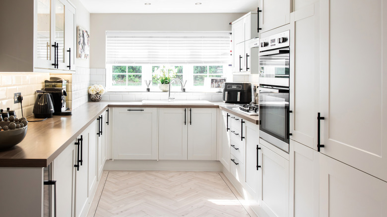 A general interior view of a new white fitted kitchen with black handles