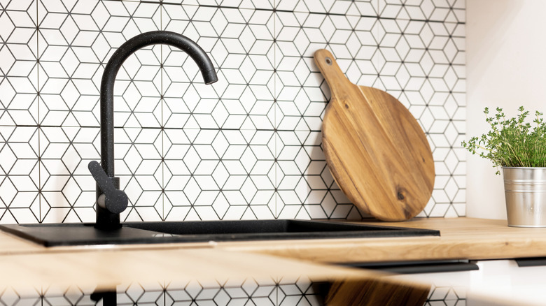 A modern kitchen with a black and white, geometric tiled backsplash.