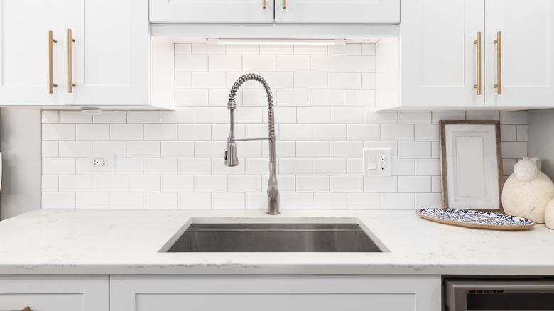 A modern kitchen with a white subway tile backsplash and white cabinets.