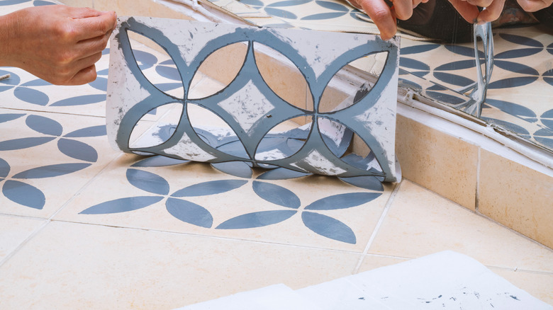 Woman using paint stencil on tile