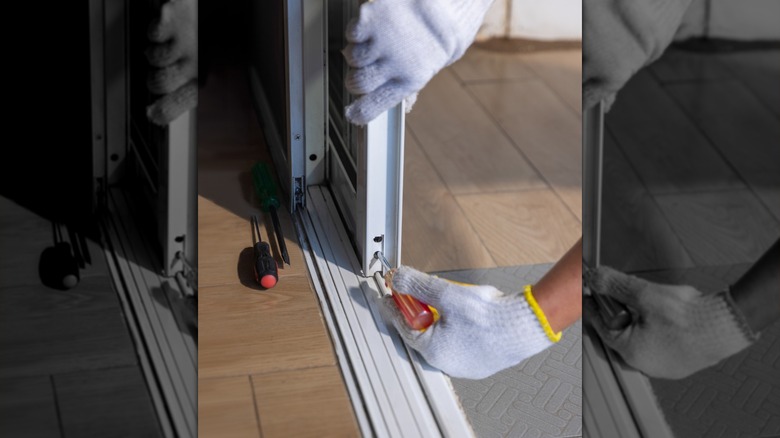 A close up of a person installing shutters to a sliding glass door frame.