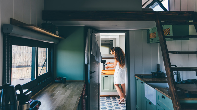 Woman in tiny home bathroom running water in the sink