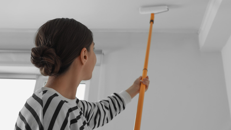 Woman painting ceiling with roller