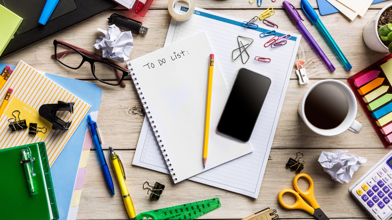 A messy desk covered with lots of office supplies.