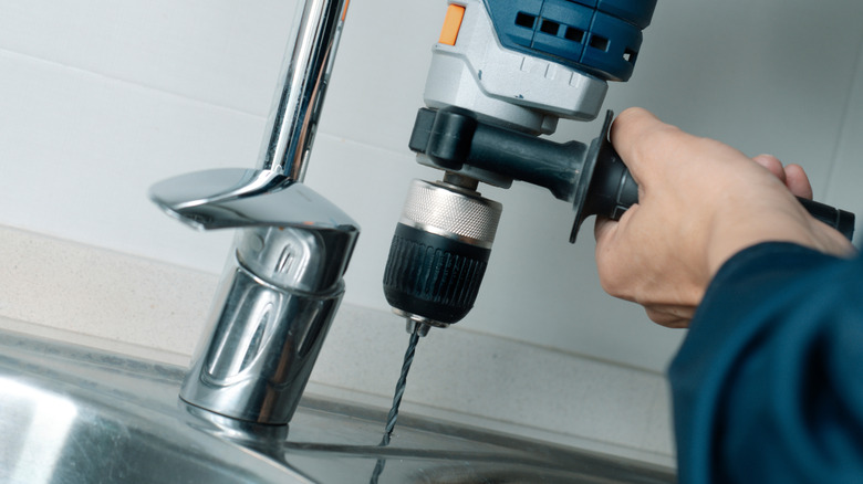 Person drilling into metal sink