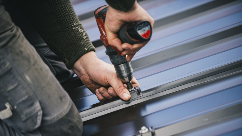 Person drilling into metal roofing sheet