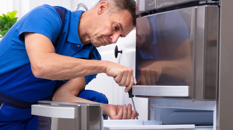 Man fixing broken refrigerator