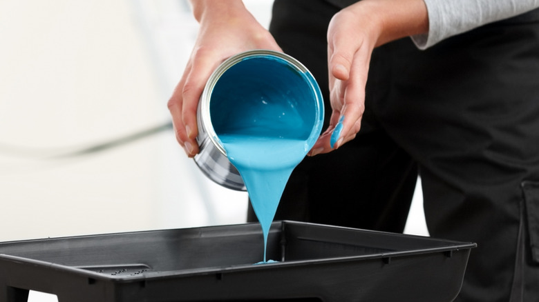 Someone pouring out a can of blue paint