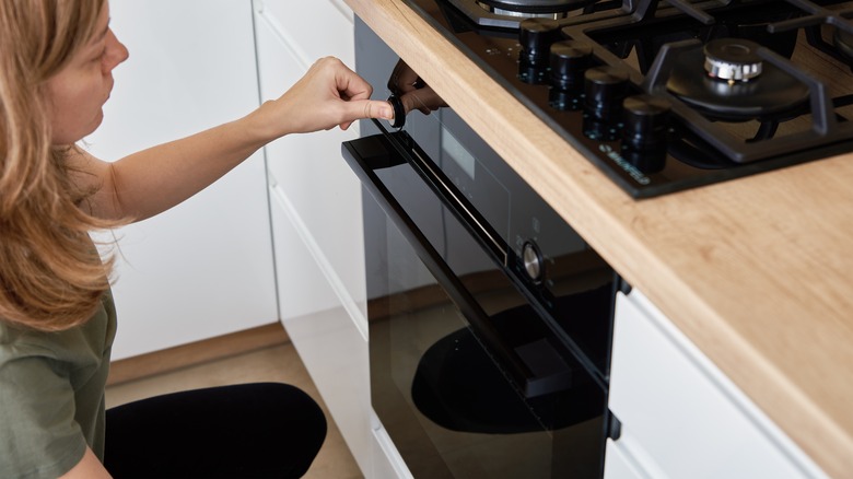 Woman pressing buttons on oven