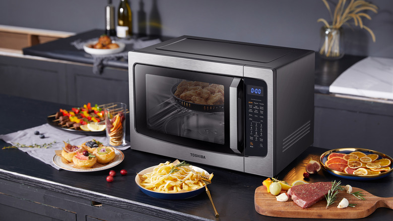 Toshiba 4-in-1 microwave oven on a kitchen island with various dishes in front of it