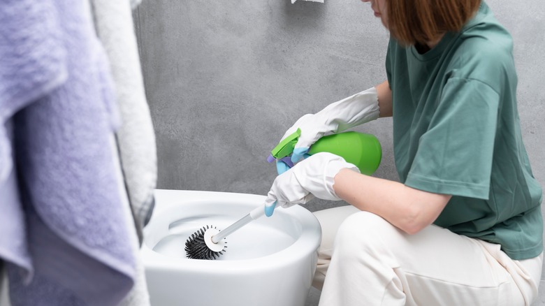 Woman cleaning toilet bowl